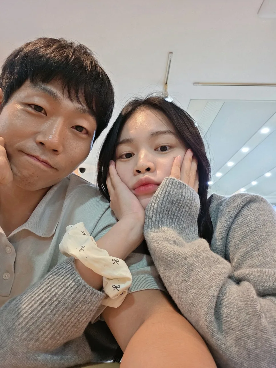 실내에서 두 손으로 얼굴을 받치고 나란히 셀카를 찍은 부부