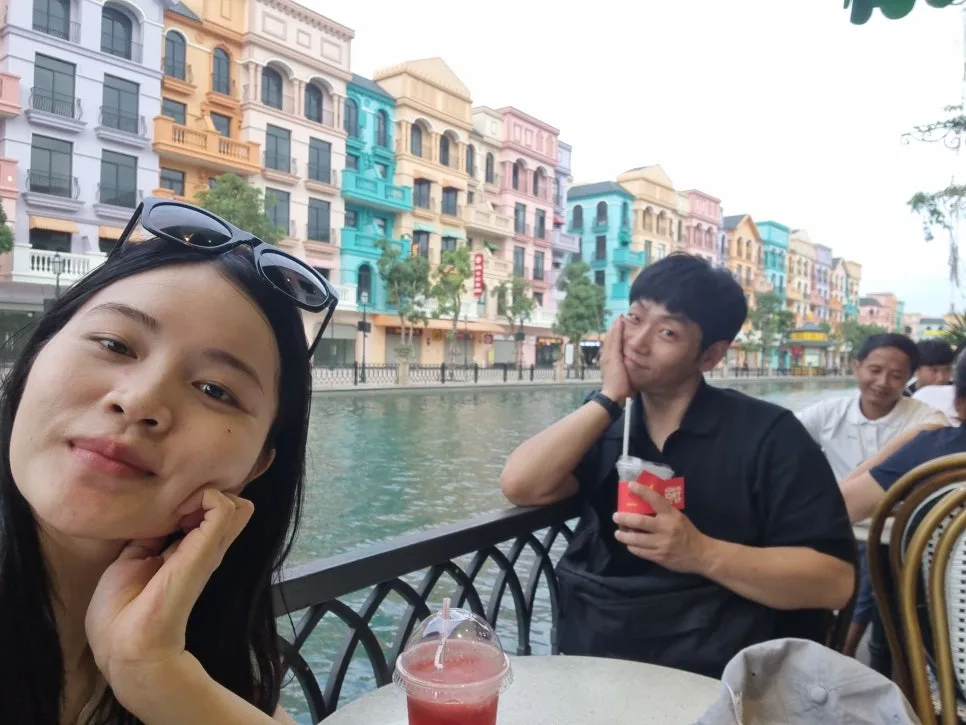 알록달록한 건물이 늘어선 운하 옆 카페에서 음료를 마시며 쉬는 부부