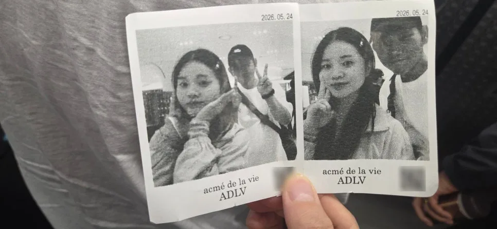 2026년 5월 24일 날짜가 찍힌 흑백 즉석사진 두 장을 손에 들고 있는 모습